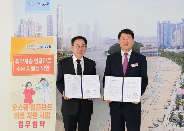 홍성조 오스템임플란트 생산총괄본부장(왼쪽)과 김성수 부산 해운대구청장이 '취약계층 임플란트 수술 지원을 위한 업무협약' 체결식에서 기념촬영을 하고 있다. 오스템임플란트는 1000만원 상당의 구강관리용품도 함께 기탁했다.[사진제공=오스템임플란트]