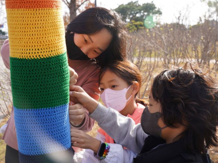 행사 참가자들이 가로수에 겨울옷을 입히고 있다.