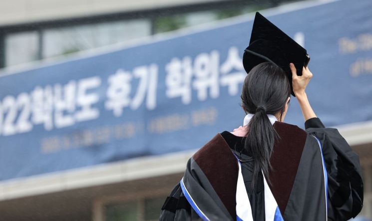 8月22日，在首尔麻浦区弘益大学举行的2022学年度后期学位授予仪式上，一名毕业生用学士帽遮住头部奔跑。联合新闻供图