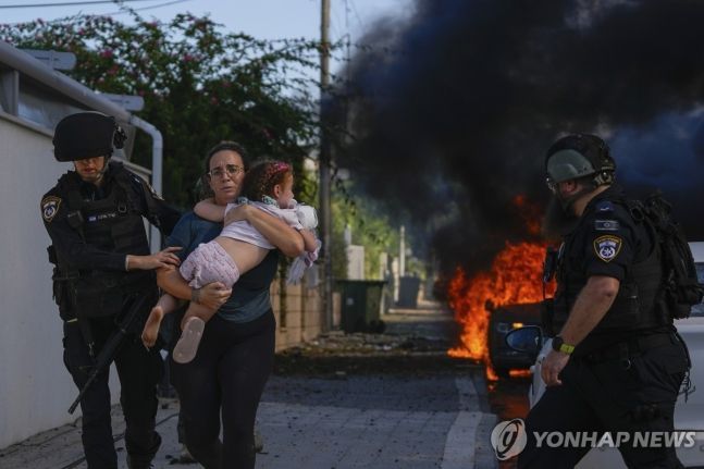 하마스 로켓 공격에 아이 안고 대피하는 이스라엘 여성 [사진출처= AP/연합뉴스)