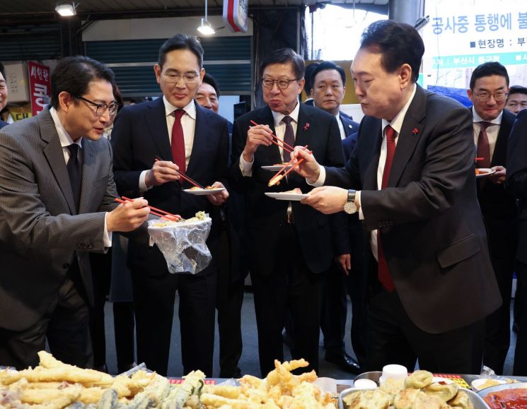 윤석열 대통령이 6일 부산 중구 깡통시장에서 재계 총수들과 분식을 맛보며 이재용 삼성전자 회장, 조현준 효성그룹 회장에게 빈대떡을 나눠주고 있다. [이미지출처=연합뉴스]