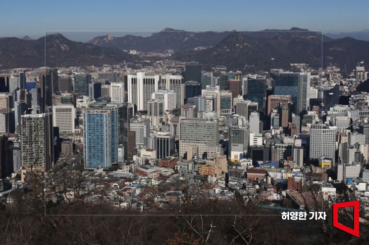 서울 남산에서 내려다본 도심의 빌딩 숲에 오후의 햇빛이 비치고 있다. 사진 속 실선 바깥은 포토샵의 생성형 확장 기능으로 만들어진 가상의 이미지다.