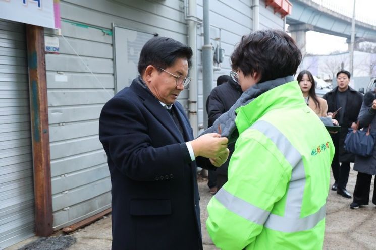 박강수 마포구청장이 환경미화원에게 목도리 핫팩을 달아주고 있다.