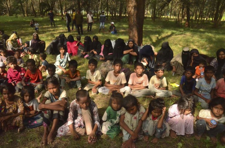 1일(현지시간) 인도네시아 아체주 동부 쿠알라 파렉 비치 숲 그늘에 미얀마에서 배를 타고 온 로힝야족 난민 어린이와 여성들이 앉아 있다. 지난해 방글라데시나 미얀마에서 배를 타고 탈출한 로힝야족 난민은 약 4천500명에 달하며 이들 중 569명은 사망하거나 실종됐다. [이미지출처=연합뉴스]