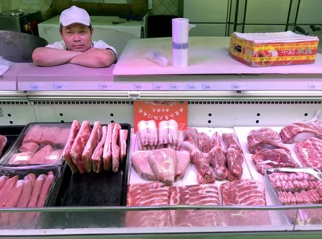 중국 베이징 한 마트의 정육점 종업원이 고기가 진열된 매대 앞에서 손님을 기다리고 있다. [사진출처= 베이징/UPI 연합뉴스]