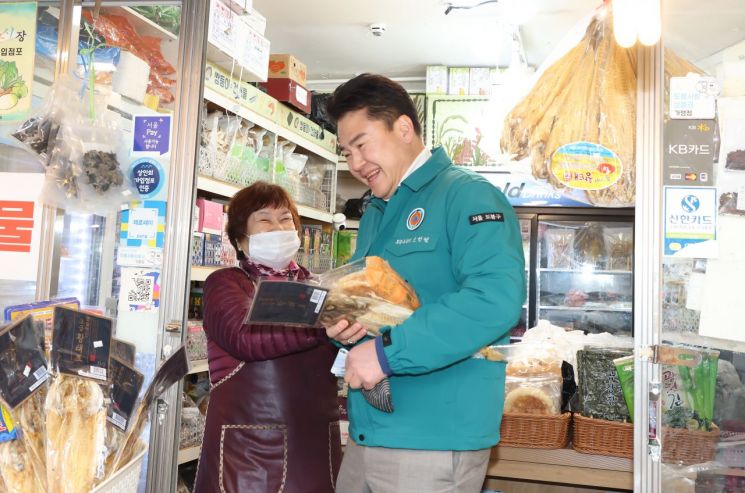 오언석 도봉구청장이 전통시장을 찾아 물건을 산 후 상인과 대화를 나누며 웃고 있다.