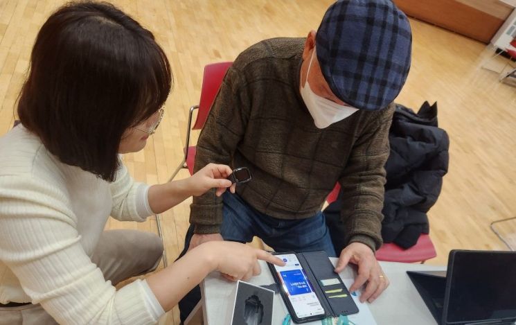 화성시 관계자가 관내 어르신에게 손목활동량게와 스마트폰을 이용한 건강관리 방법을 안내하고 있다. [사진제공=화성시]