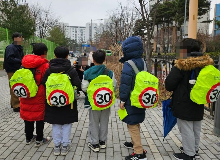 12일 마포구 상암동 하늘초등학교 학생들이 스쿨존 제한속도가 표기된 가방 덮개를 착용한 채 나란히 서있다. [사진=이지은 기자]
