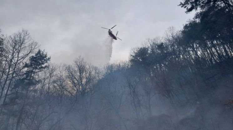 소방헬기가 공장 화재 현장에서 야산으로 번진 불을 끄고 있다. [사진제공=경남소방본부]