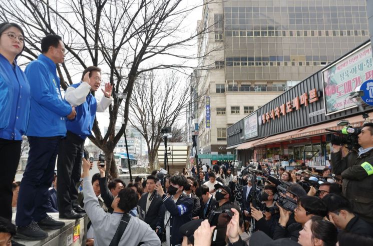 이재명 더불어민주당 대표가 27일 충북 청주시 청원구의 상가 밀집 지역을 방문해 거리 시설물 위에서 시민들에게 인사하고 있다. [이미지출처=연합뉴스]