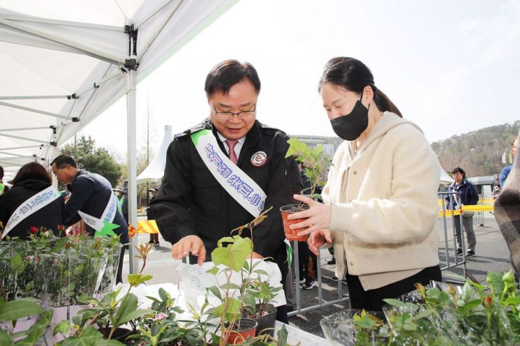 홍남표 창원특례시장이 시민에게 나무를 나눠주고 있다.