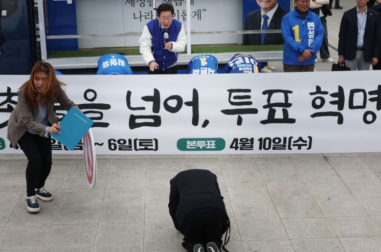 더불어민주당 이재명 대표가 4일 부산역 광장에서 이 지역 후보들과 함께 사전투표를 독려하던 중 한 여성이 큰절을 하자 이를 만류하고 있다. [사진출처=연합뉴스]