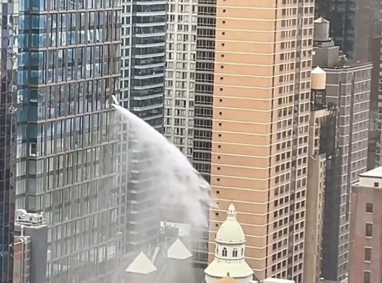 지난 4일(현지시간) 미국 뉴욕 맨해튼 헬스키친의 한 고층건물에서 창문 밖으로 거대한 물줄기가 뿜어져 나오고 있다.[이미지출처=사회관계망서비스(SNS) 캡처]
