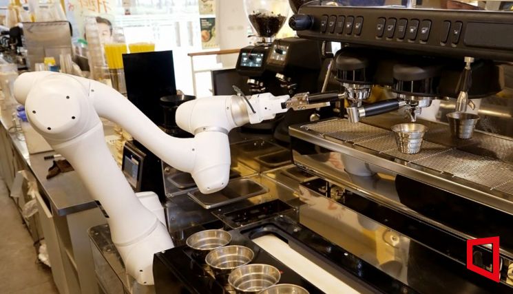 두산로보틱스 협동로봇이 원두가 담긴 포터필터를 커피머신에 장착하고 있다.(제공=두산로보틱스)