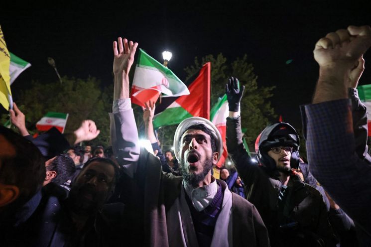 이란이 이스라엘에 드론과 미사일 공격을 가한 후 테헤란의 영국 대사관 앞에 모인 시위자들이 이란의 국기와 팔레스타인 국기를 흔들고 있다. [이미지출처=AFP연합뉴스]