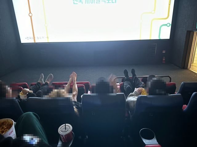 두 발을 앞좌석에 올리고 영화를 관람하고 있는 사람들. [사진=온라인 커뮤니티 갈무리]