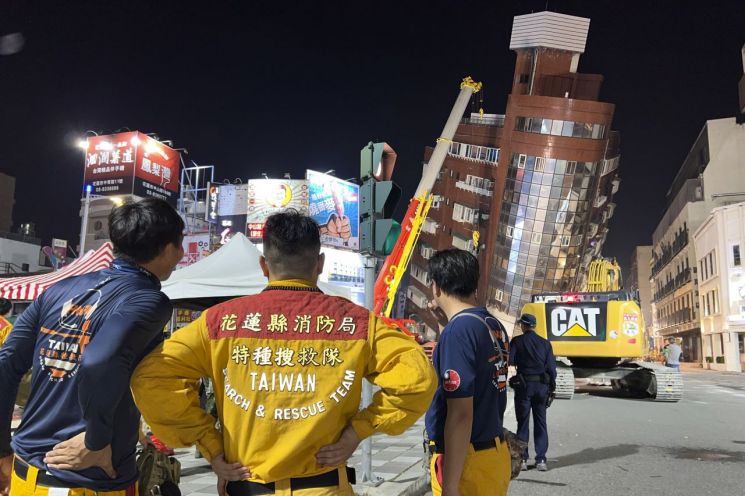 3일 대만 동부 지역에서 발생한 규모 7.4 강진의 영향으로 심하게 기울어진 화롄 시내 건물을 구조대원들이 쳐다보고 있다. [이미지출처=연합뉴스]