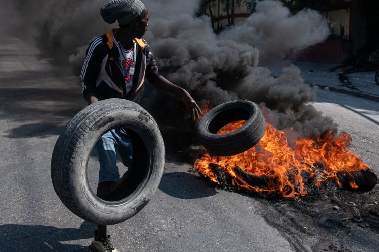 지난달 12일(현지시간) 아이티 포르토프랭스에서 시위대가 타이어에 불을 붙이고 있다. [이미지출처=EPA연합뉴스]