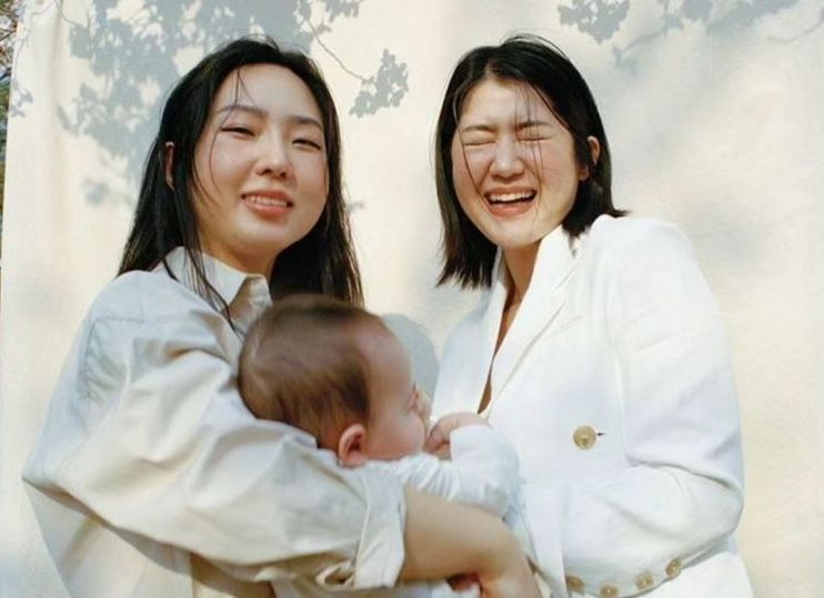 동성 커플 김규진(오른쪽)·김세연 씨가 딸 '라니'(태명)를 안고 있다. [이미지출처=코스모폴리탄 홈페이지 캡처]
