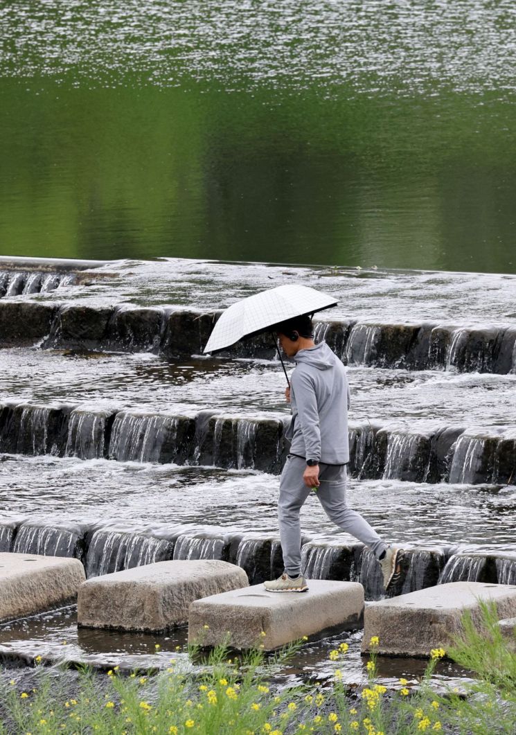 광주 서구 광주천에서 한 시민이 우산을 쓰고 징검다리를 건너고 있다. [이미지출처=연합뉴스]