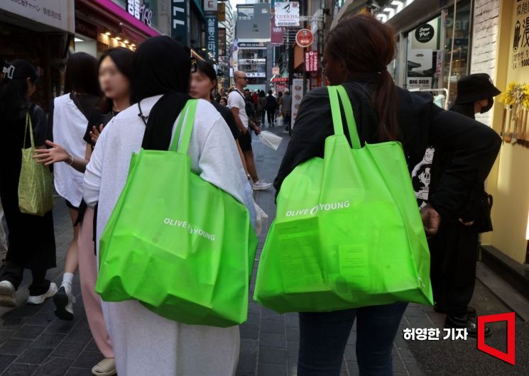 As Myeongdong in Seoul buzzes with foreign tourists, visitors walk down the street carrying shopping bags filled with cosmetics.