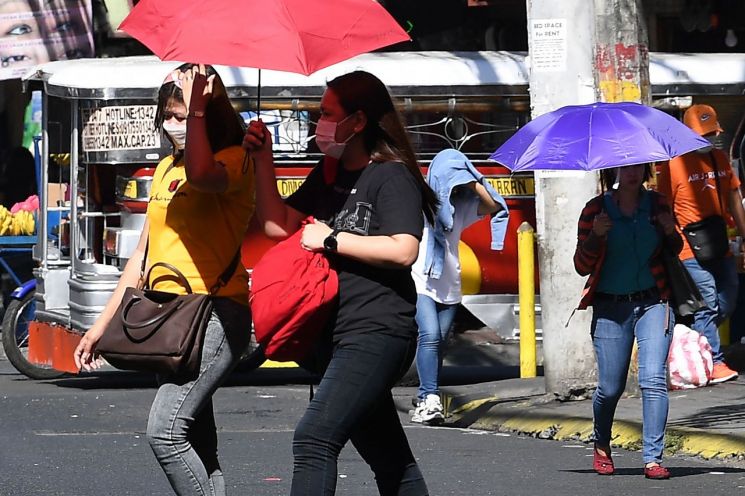 지난달 29일 이례적 폭염이 덮친 필리핀 마닐라 시내에서 여성들이 뜨거운 햇빛을 가리기 위해 양산을 쓰고 걸어가고 있다. 사진제공=연합뉴스