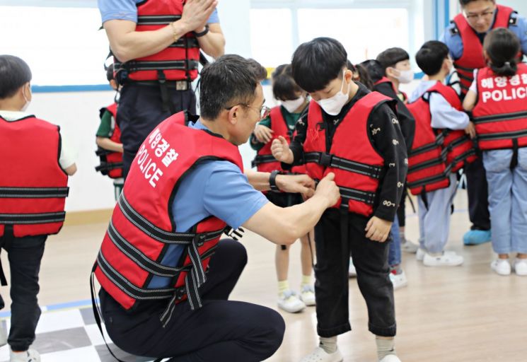 김영철 창원해경서장이 창원 마산신월초 학생에게 구명조끼를 입혀주며 착용법을 설명하고 있다. [사진제공=창원해양경찰서]