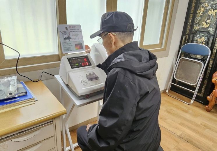기장군에 위치한 경로당을 방문한 어르신이 혈압측정기를 사용하고 있다.