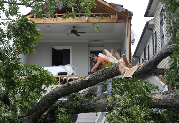 텍사스 휴스턴 일대에 불어닥친 강풍으로 쓰러진 나무를 썰고 있는 남성의 모습 [이미지출처=AP연합뉴스]