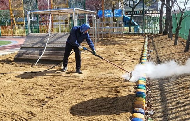 광주 서구에 관내 모래놀이터에 고온 스팀 소독을 하고있다.[사진제공=서구]