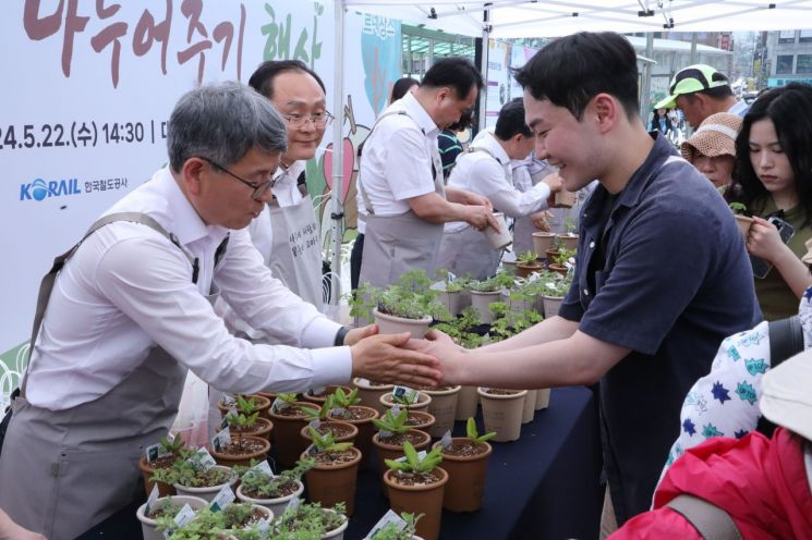 류광수 한수정 이사장이 22일 대전역 광장에서 시민의 손을 맞잡으며, 자생식물을 선물하고 있다. 한국수목원정원관리원 제공