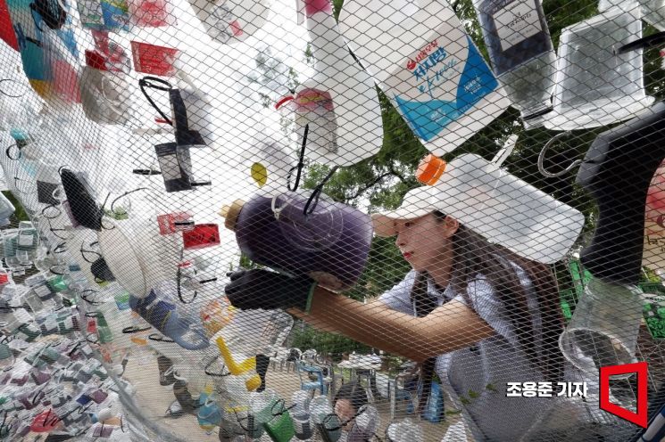 환경의 날인 5일 서울 종로구 환경운동연합에서 열린 '플라스틱 구토' 행사, 참가자가 대형 그물 조형물에 폐플라스틱을 걸고 있다. 이번 행사는 눈앞에서 쏟아지는 플라스틱을 더 이상 감당하지 못한 지구가 플라스틱을 토해낸다는 의미를 담고 있다. 사진=조용준 기자 jun21@
