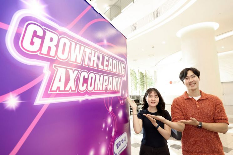 LG유플러스 직원들이 신규 슬로건 ‘Growth Leading AX Company’를 소개하고 있다/사진=LG유플러스