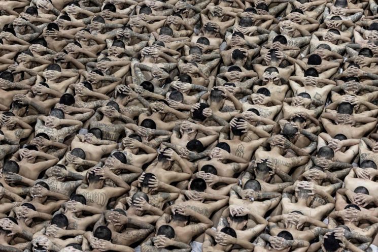 지난 11일(현지시간) 엘살바도르 대통령실에서 공개한 사진. 웃옷을 벗은 수감자들이 머리에 손깍지를 낀 채 바닥에 앉아 있다. [이미지출처=AFP연합뉴스]