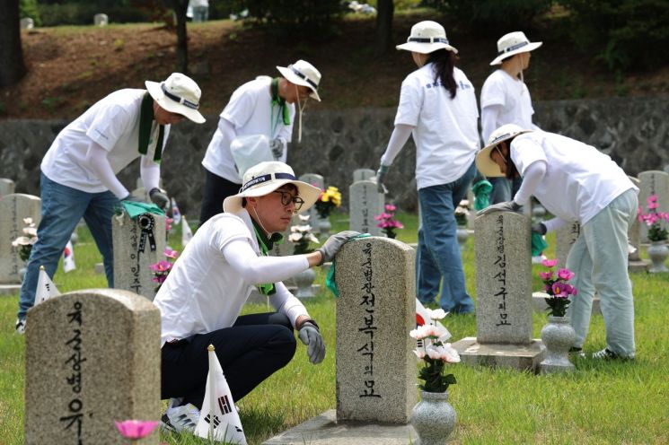 지난 14일 서울 동작구 국립서울현충원 묘역에서 HD현대 임직원들이 묘역 정비 봉사 활동을 하고 있다. [사진제공=HD현대]