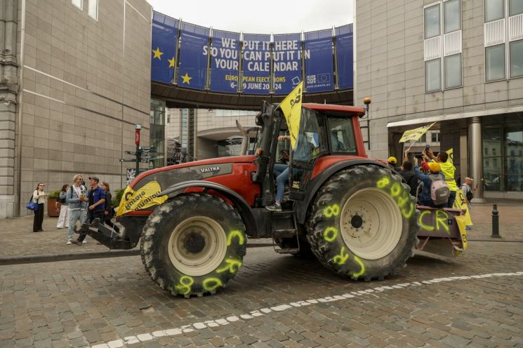 4일(현지시간) 벨기에 브뤼셀의 유럽의회 청사 앞에서 농민들이 트랙터를 세워놓고 탄소세 반대 시위를 하고 있다. [이미지출처=AP·연합뉴스]