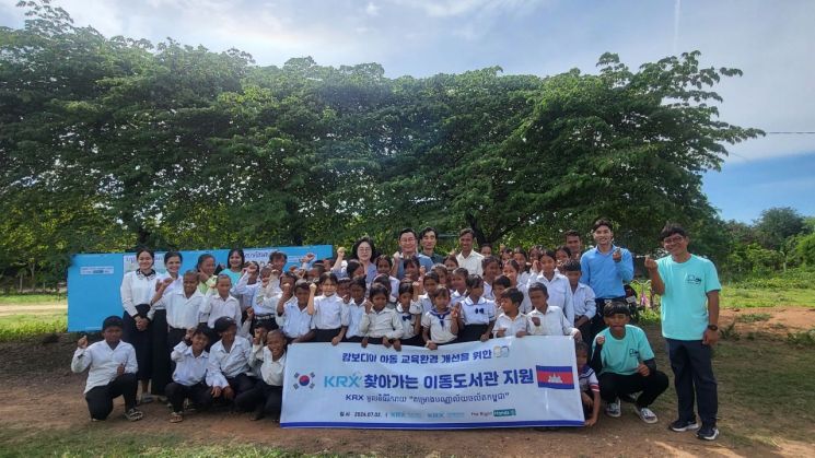 황우경 KRX국민행복재단 사무국장(가운데 좌측), 손정배 더라이트핸즈 대표(가운데 우측)가 캄보디아 오우다 초등학교 교사 및 학생들과 기념 촬영을 하고 있다. [사진제공=한국거래소]