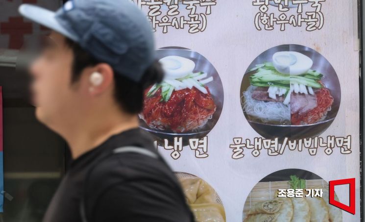서울의 한 먹자골목의 냉면전문점 앞을 시민들이 지나가고 있다. 조용준 기자 jun21@