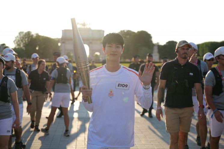 그룹 방탄소년단(BTS)의 맏형 진이 14일(현지시간) 프랑스 파리 루브르 박물관 근처에서 파리올림픽 성화를 봉송하며 손을 흔들고 있다. [사진제공=2024 파리 올림픽 조직위원회]