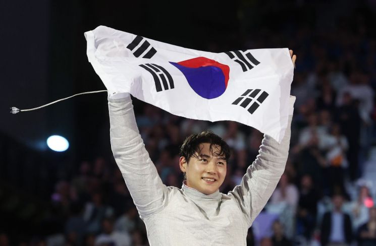 Osangwook, who won the gold medal in the men's sabre fencing event at the 2024 Paris Olympics, is celebrating while holding the Taegeukgi flag. <br>[Photo by Yonhap News]