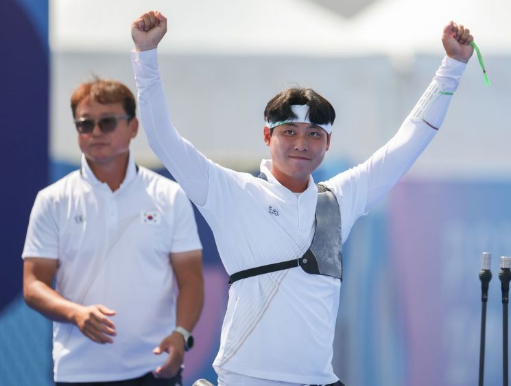 31일(현지시간) 프랑스 파리 레쟁발리드 양궁 경기장에서 열린 2024 파리올림픽 양궁 남자 개인전 64강전에서 이우석이 경기에 승리한 뒤 손을들어 기뻐하고 있다. 왼쪽은 박성수 감독. [이미지출처=연합뉴스]