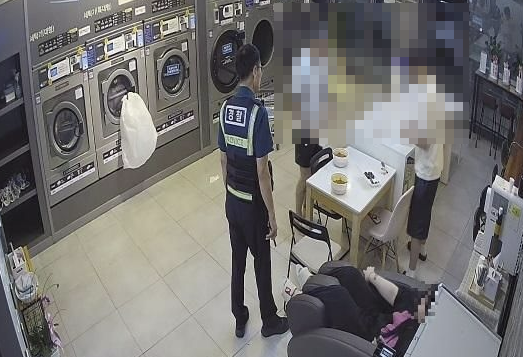 무인세탁방을 식당처럼 이용하던 사람들이 업주 신고를 받고 온 경찰을 만나고 있다. [사진캡처=한국일보]