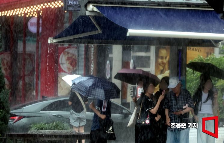 5일 서울 강남역 사거리 부근에서 갑자기 쏟아지는 소나기에 우산을 준비하지 못한 시민들이 그늘막 아래에서 피하고 있다. 사진=조용준 기자 jun21@
