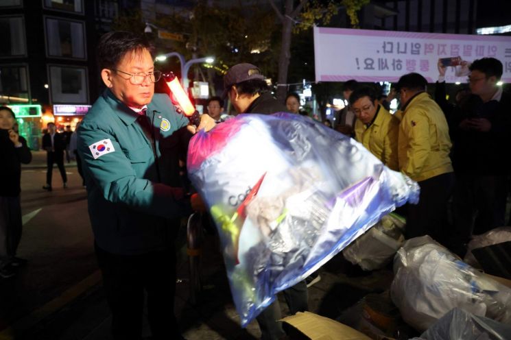 박강수 마포구청장이 지난해 10월 27일 홍대 레드로드 안전 관리 점검을 위해 거리 쓰레기를 치우고 있다.