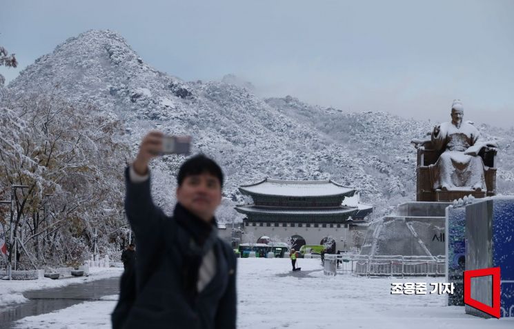 서울 전역에 많은 눈이 내린 27일 서울 종로구 경복궁과 북악산이 하얗게 내린 눈으로 덮히자 직장인들이 휴대폰에 풍경을 담고 있다. 조용준 기자