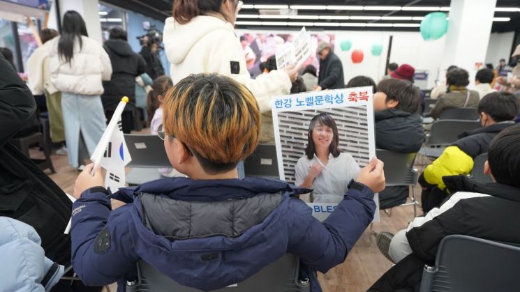 10일 광주 북구서 열린 한강 작가의 노벨문학상 수상 축하 행사에 참석한 소년이 태극기와 포스터를 들고 있다. 송보현 기자