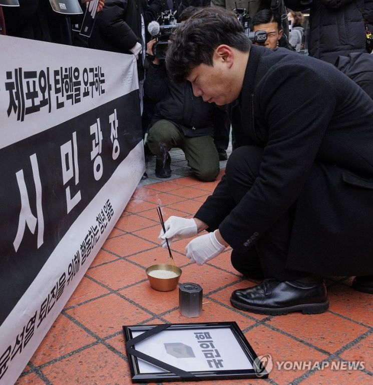 11일 오전 서울 여의도 국민의힘 당사 앞에서 윤석열 퇴진을 위해 행동하는 청년 일동(윤퇴청)이 주최한 '국민의힘 해체'를 위한 장례식에서 참가자 대표가 장례의식을 시작을 알리며 향에 불을 붙이고 있는 모습. 연합뉴스