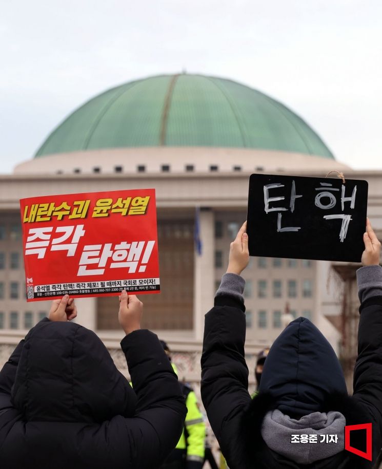 윤석열 대통령 탄핵 2차 표결을 하루 앞둔 13일 서울 여의도 국회의사당 앞에서 밤샘을 한 시민들이 이른 아침부터 피켓을 들고 탄핵을 촉구하고 있다. 조용준 기자