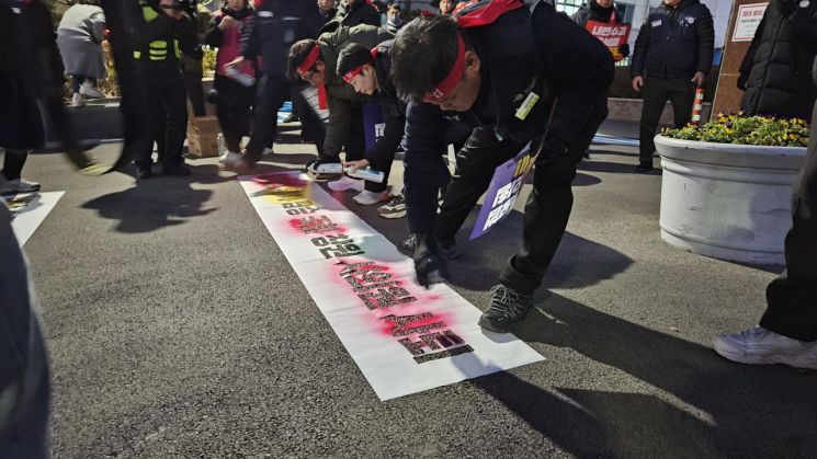 민주노총 경남본부가 창원시의회 입구 앞 바닥에 창원시의원을 규탄하는 문구를 분사형 도료로 새기고 있다. 이세령 기자