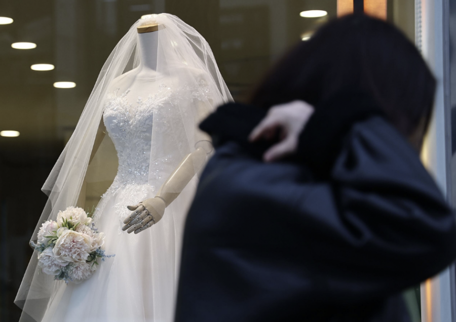 서울 마포구 아현동 웨딩거리에서 한 시민이 웨딩드레스가 입혀진 마네킹 앞을 지나고 있다. 연합뉴스